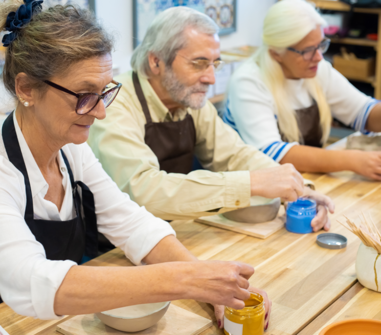 3 starsze osoby mieszają farby malują ceramikę warsztaty