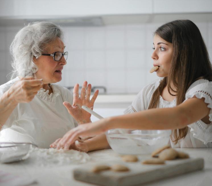 dwie kobiety starsza młodsza wyrabiają ciasto na ciastka rozmawiają 
