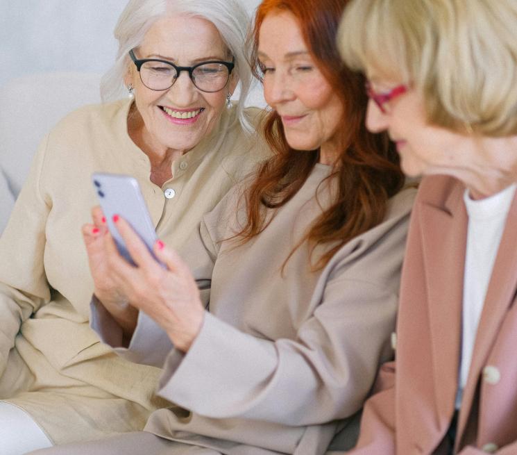 trzy starsze kobiety patrzą w smartfona