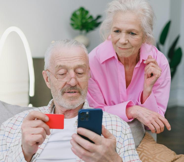 zdjęcie para seniorów mężczyna siedzi na kanapie trzyma telefon i kartę płatniczą