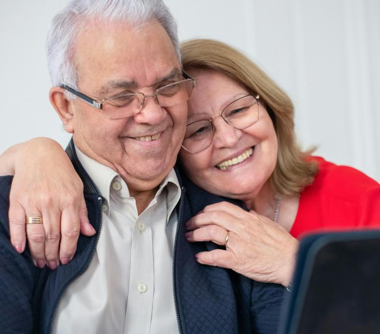 zdjęcie para przytulonych senioró patrzy na tableta
