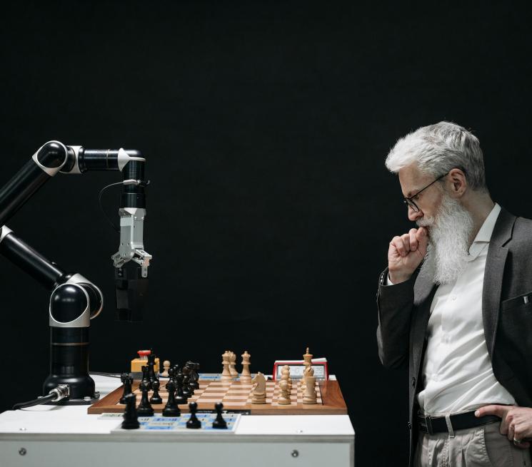 zdjęcie starszy mężczyzna w garniturzegra w szachy z robotem
