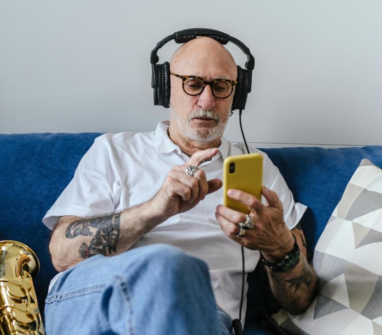 zdjęcie starszy mężczyzna słucha muzyki na telefonie i przez słuchawki
