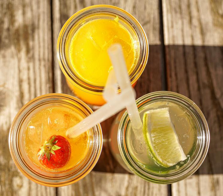 zdjęcie z góry trzy szklanki wypełnione napojami lemoniadami z cytryną truskawą i pomarańczą