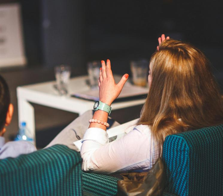 zdjęcie kobieta i mężczyzna siedzą tyłem biorą udział w panelu dyskusyjnym kobieta gestykuluje