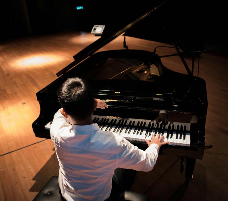zdjęcie pianista siedzi tyłem plecami do obiektywu gra na fotepianie 