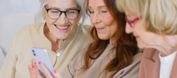 trzy starsze kobiety patrzą w smartfona