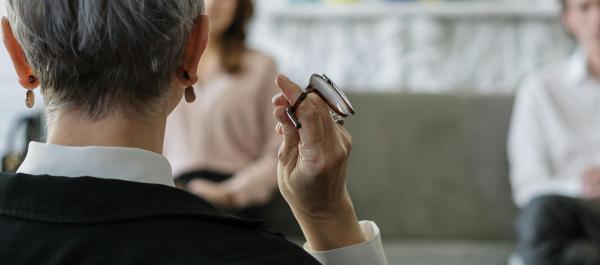 zdjęcie osoba siędząca tyłem prowadzi rozmowę z dwójką osób