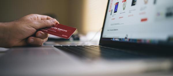 zdjęcie laptopa na ekranie sklep internetowy o laptop oparta ręka z kartą bankomatową