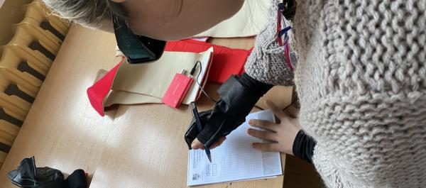 zdjęcie dziewczyna w symulatorze oddczuć starczych podpisuje się na kartce