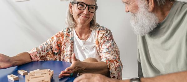 zdjęcie pary seniorów siedzących przy stole i grających w grę planszową