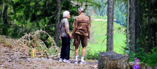 zdjęcie para seniorów trzymająca się za ręce stoi w lesie