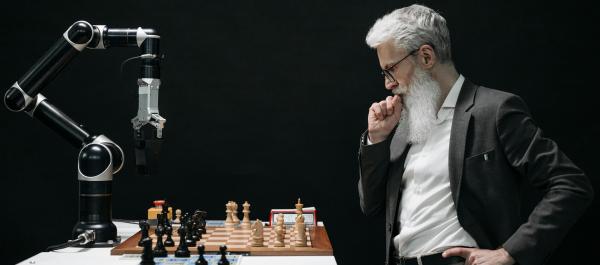 zdjęcie starszy mężczyzna w garniturzegra w szachy z robotem