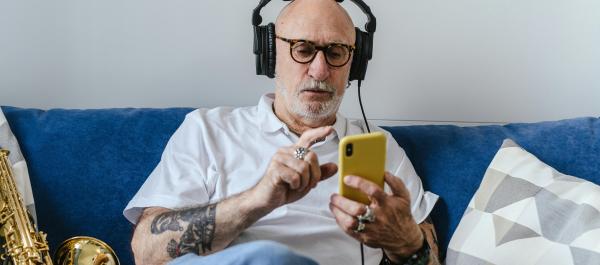 zdjęcie starszy mężczyzna słucha muzyki na telefonie i przez słuchawki