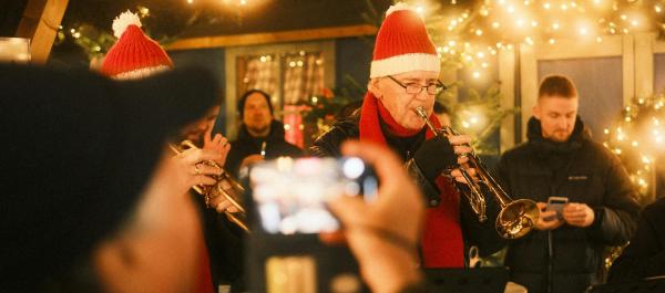 zdjęcie na pierwszym planie osoba robi zdjęcie zespołowi muzycznemu występującemu w plenerze w świątecznej scenerii