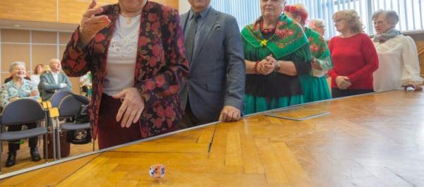 zdjęcie uśmiechnięci seniorzy stoją w kolejce do rzucenia kostką