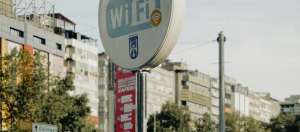 zdjęcie dwóch mężczyzn siedzi na barierce przy znaku z darmowych WIFI