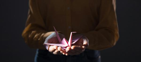 zdjęcie osoba trzymająca na dłoniach ptaka z papieru zrobionego z origami