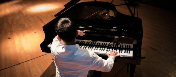 zdjęcie pianista siedzi tyłem plecami do obiektywu gra na fotepianie 