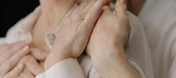 zdjęcie osoba obejmuje od tyłu drugą osobę trzymają się za ręcę 