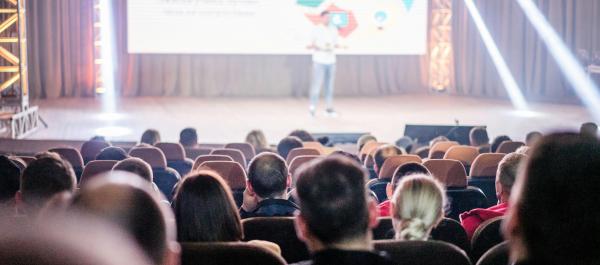 zdjęcie sala konferencyjna rząd krzeseł zdjęcie osób siedzących tyłem na scenie prelegent