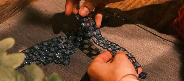 zdjęcie dłonie kobiety przygotowującej pracę artystyczną nakłada na obraz fragmenty materiału