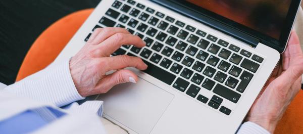 zdjęcie starsza osoba pisze na klawiaturze laptopa
