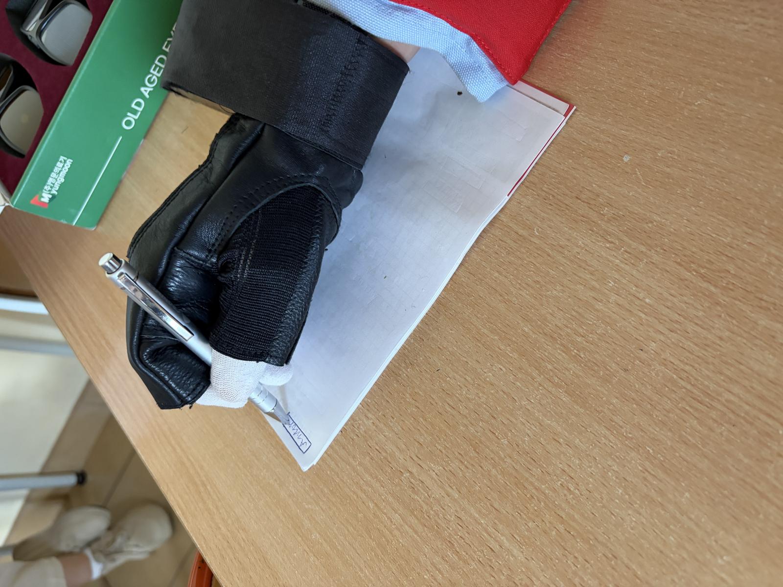 zdjęcie osoba z symulatorem drżenia rąk podpisuje się na kartce