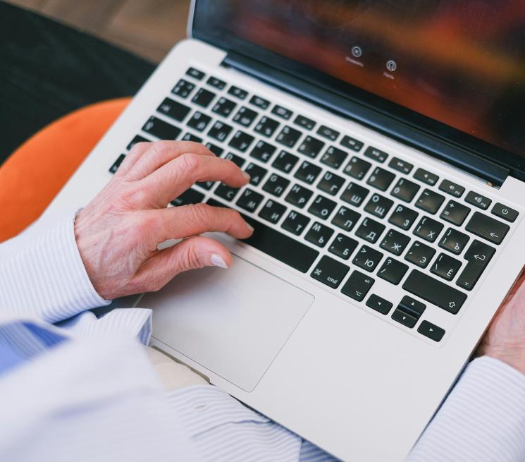 zdjęcie starsza osoba pisze na klawiaturze laptopa
