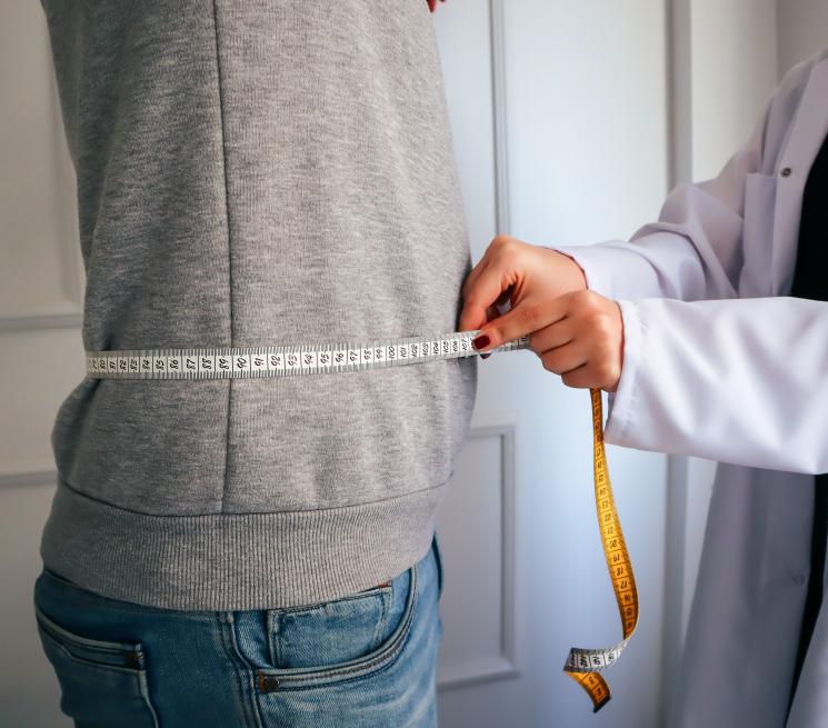 zdjęcie lekarka dietetyk kobieta w kitlu mierzy mężczyznę z pasie