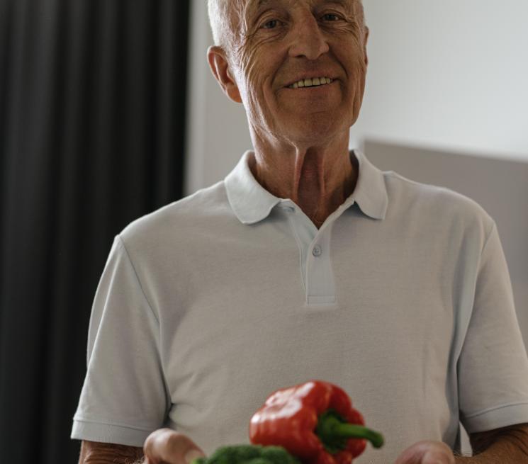 zdjęcie uśmiechnięty senior trzyma miskę warzyw