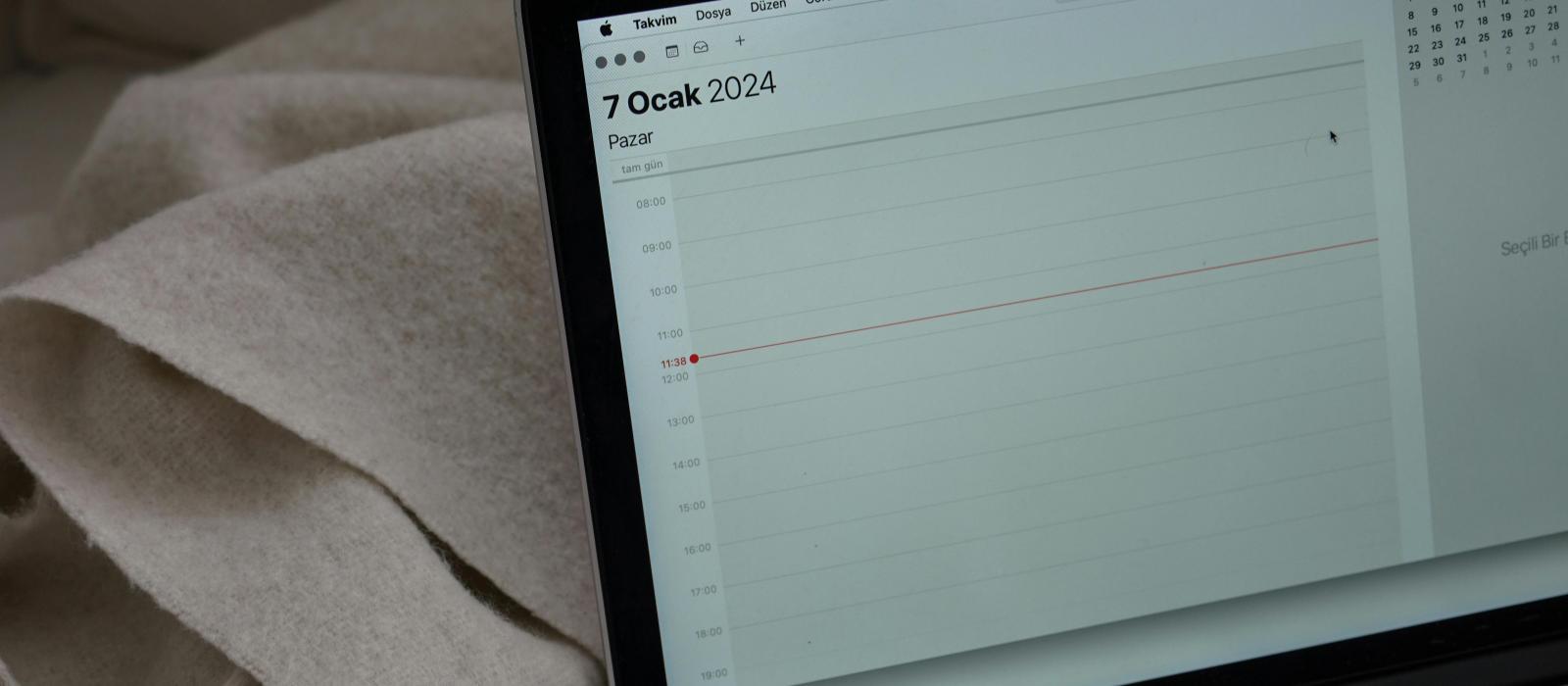 zdjęcie otwarty laptop na ekranie otwarta aplikacja kalenarza na laptopie leży filiżanka z kawą obak otwarty notes